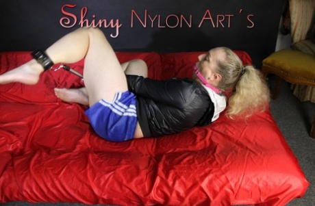 Blonde girl sports a ball gag while attaching herself to a spreader bar 50861315