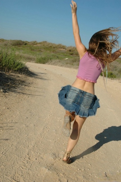 Young girl frolics on a dirt road well wearing a denim miniskirt and a thong 65481150