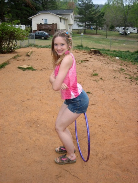 Young amateur works a hula hoop during non-nude action on a patch of sand 14557162