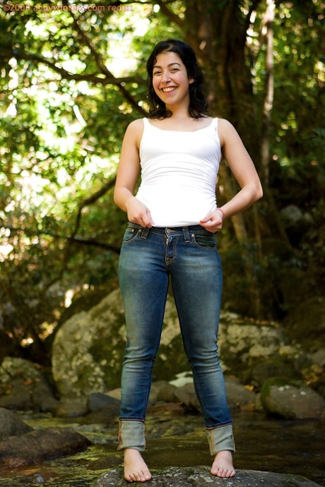 Barefoot solo girl stripping off her blouse and jeans outdoors 50411470